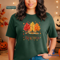 A woman modeling a heather dark green t-shirt with a colorful autumn tree graphic and the text 'Change is Beautiful'. 