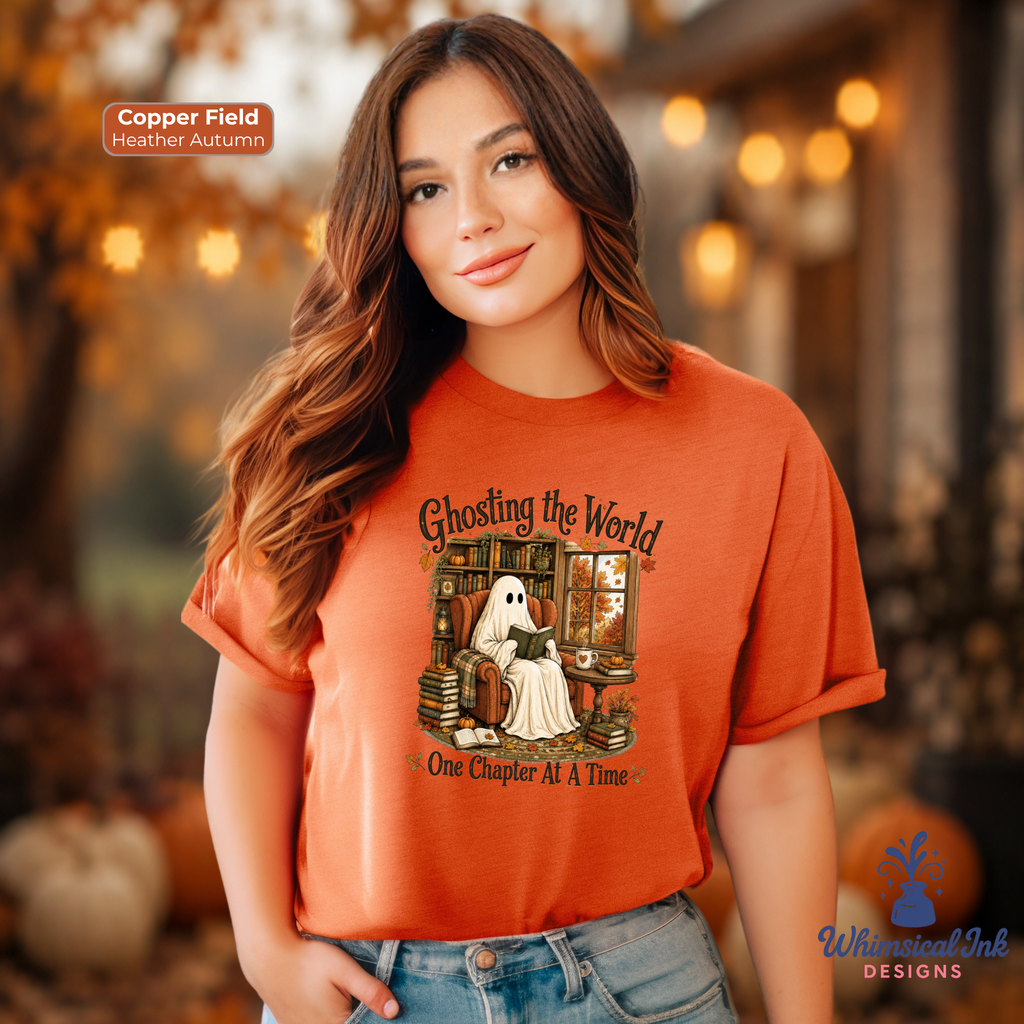 A woman wearing a copper-orange graphic t-shirt with a ghost sitting at a desk and the text 'Ghosting the World One Chapter At A Time'. The image has a warm, autumn-themed bokeh background with pumpkins and lights, and includes a 'Copper Field Heather Autumn' color label and a 'Whimsical Ink Designs' logo.
