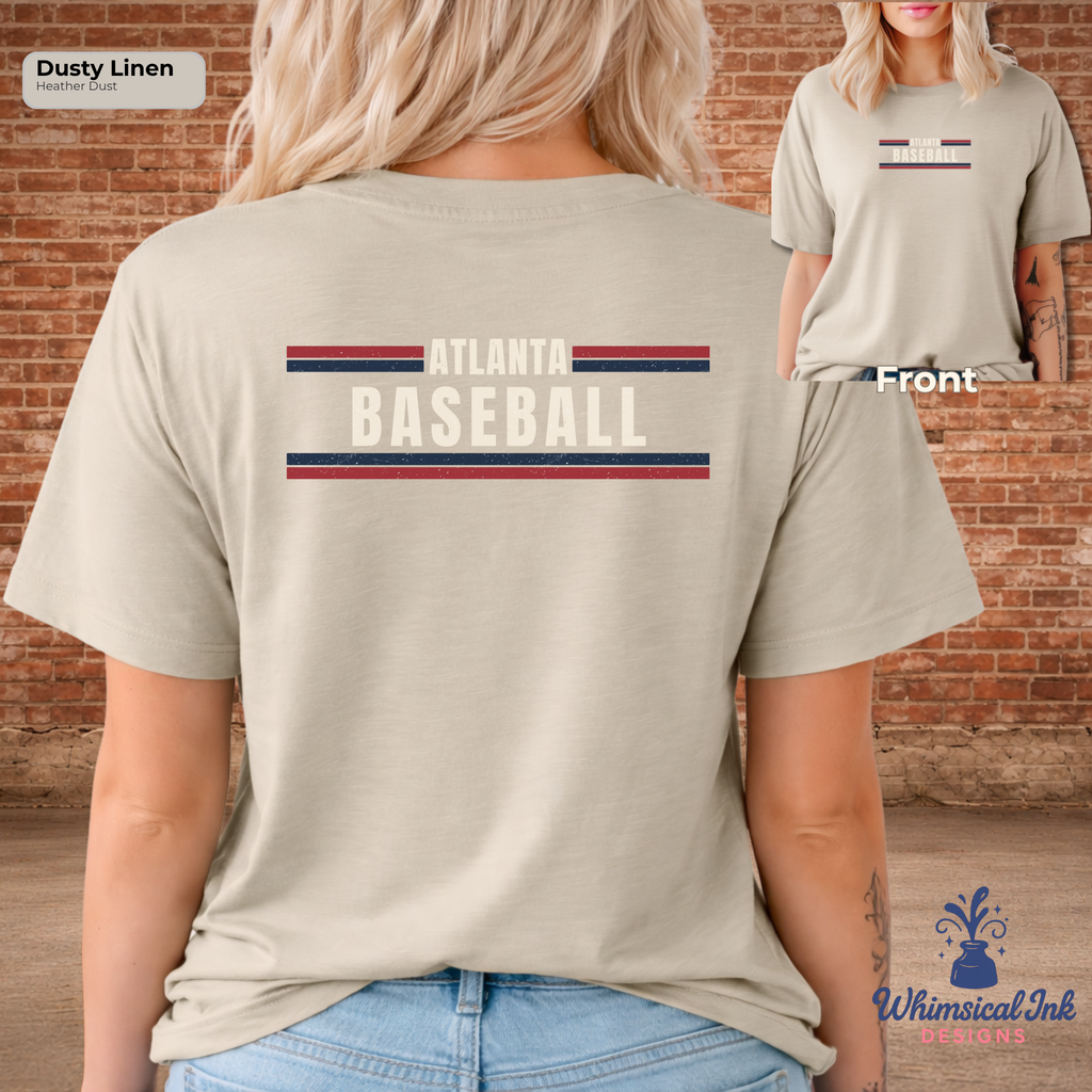 Beige t-shirt with 'Atlanta Baseball' text and stripes on the back, worn by a person against a brick wall.