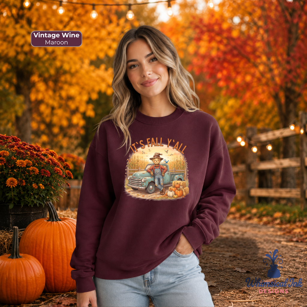 A woman wearing a maroon crewneck sweatshirt with a vintage autumn graphic, standing outdoors in a fall-themed setting with pumpkins and orange foliage.