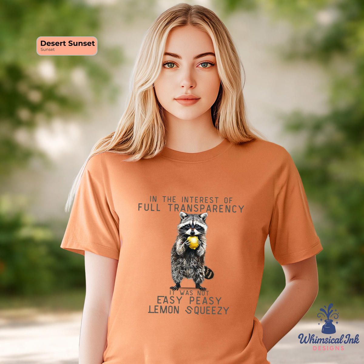 Person wearing an orange t-shirt with a raccoon graphic and text, standing outdoors.