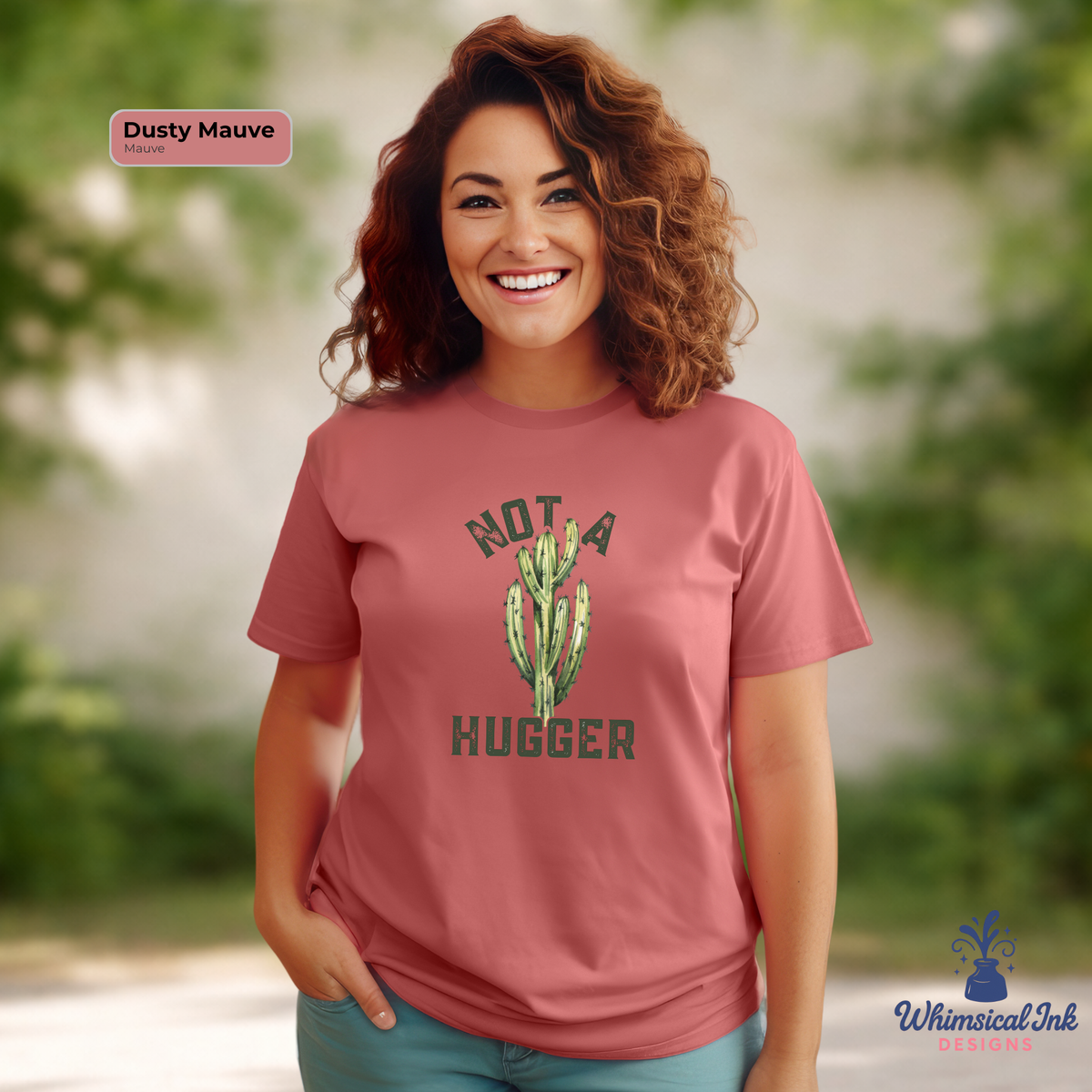Woman wearing a mauve t-shirt with a cactus graphic and text, standing outdoors.