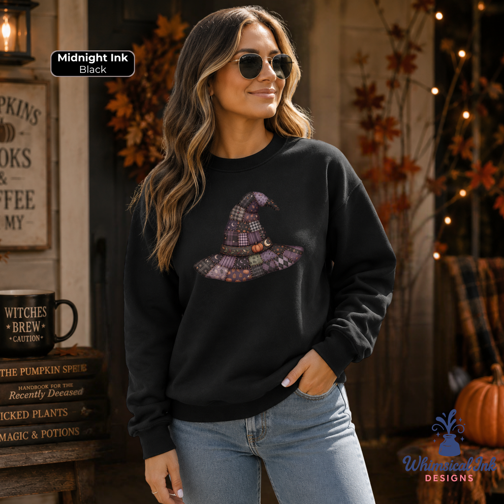 A woman wearing a black crewneck sweatshirt with a purple plaid witch hat graphic, paired with light blue jeans, set against a cozy autumn-themed background with fall decorations.
