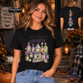 A woman models a black graphic t-shirt featuring a colorful illustration of potion bottles and the text 'Pick Your Poison'. The image includes a front view, a back view inset, and a text overlay indicating the color is 'Inkwell Black'.