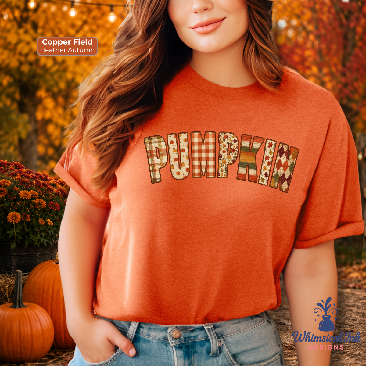 A woman wearing a copper-orange t-shirt with 'PUMPKIN' printed across the chest in a fall-themed patterned font. The background shows an autumn outdoor setting with pumpkins, orange foliage, and fall string lights.
