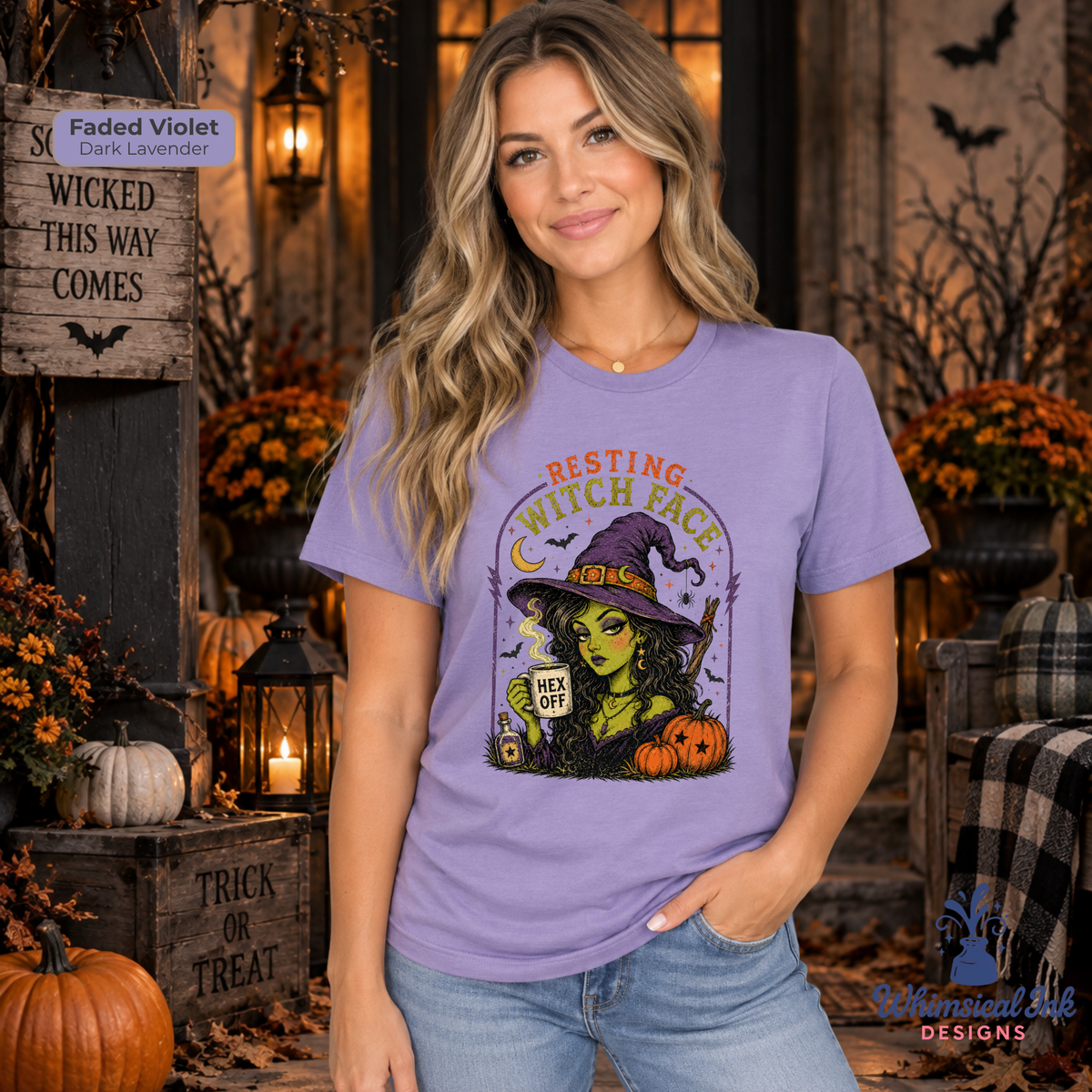 A woman wearing a faded violet graphic t-shirt with a 'Resting Witch Face' Halloween design, posed in a cozy, decorated autumn porch setting.