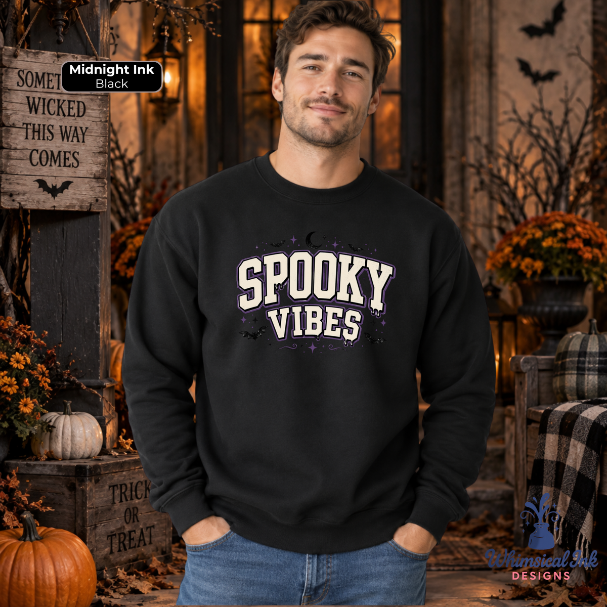 A man wearing a black crewneck sweatshirt with 'SPOOKY VIBES' printed in white and purple distressed lettering, set against a cozy, decorated autumn and Halloween background.
