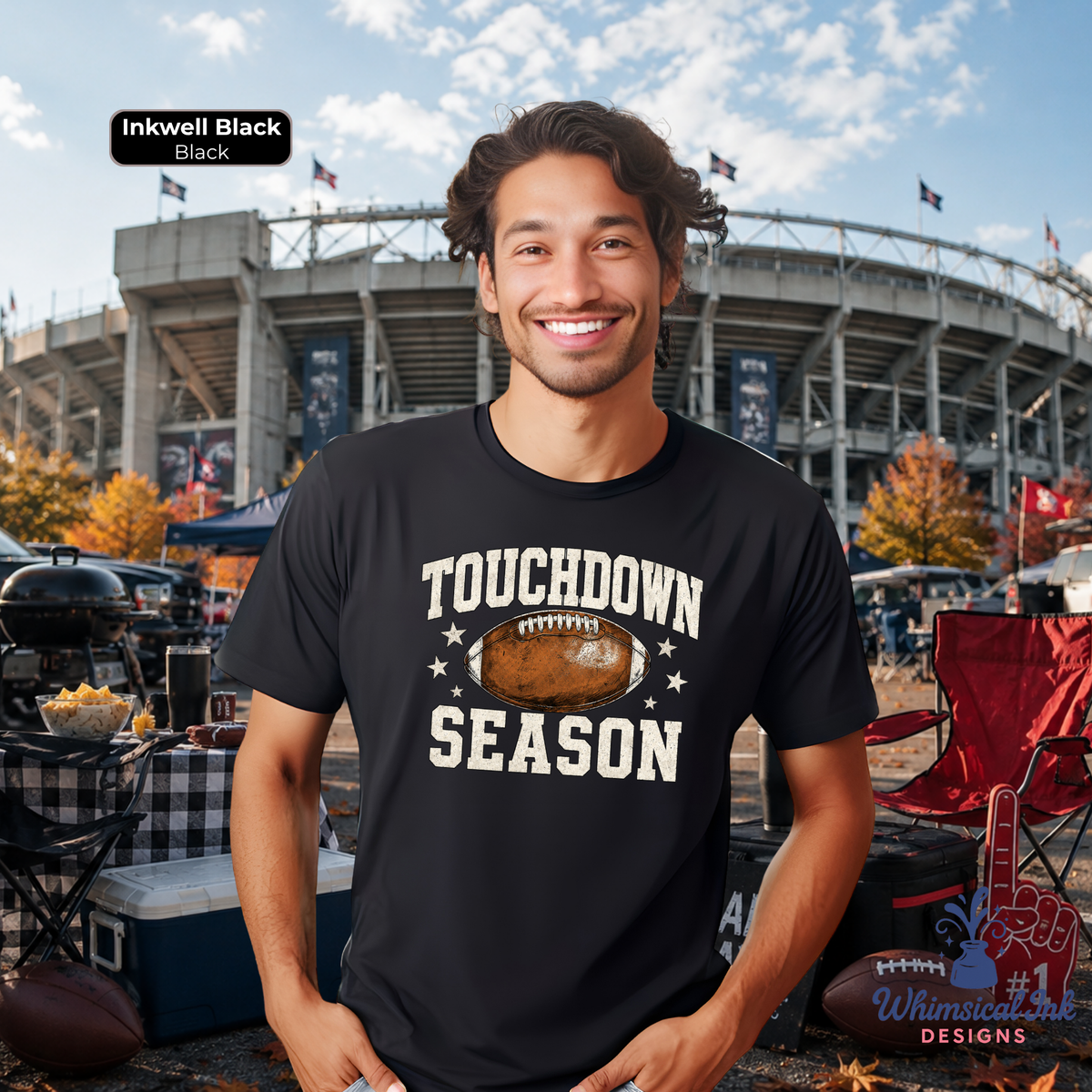 A man wearing a black graphic t-shirt with 'TOUCHDOWN SEASON' and a football design, standing in front of a stadium at an outdoor event. A label in the top left reads 'Inkwell Black'.